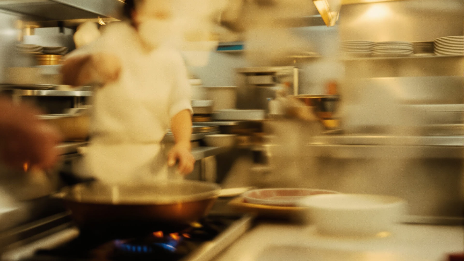 Steam and motion in a professional kitchen during service